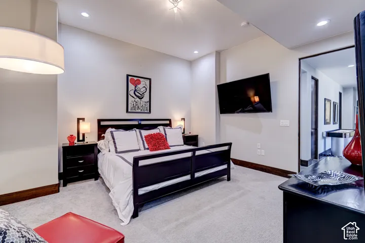 Recessed lighting, drum pendant light fixture, wall-mounted sconces, dark wood-finish trim, and light-toned carpeting