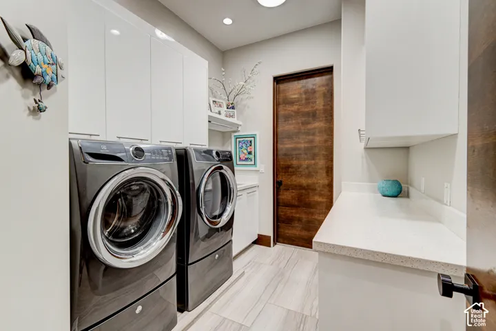 Laundry area featuring light wood-finish flooring, white cabinetry, a built-in countertop, and a wood-finish door