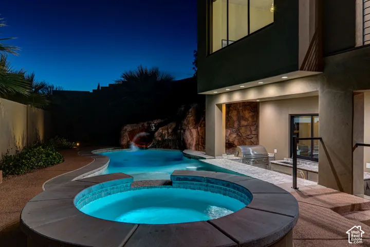 Swimming pool with integrated spa, rock water feature with slide, and built-in barbecue grill