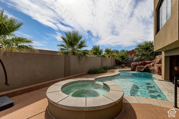 Curved swimming pool with integrated spa and rock waterfall feature