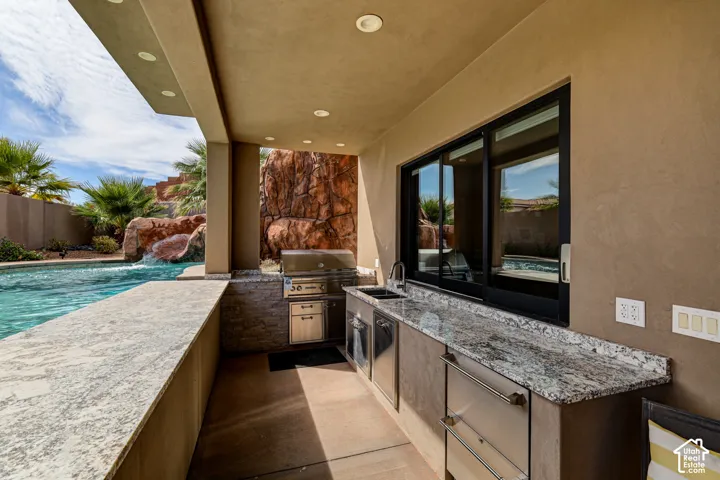 Covered outdoor kitchen featuring granite countertops, stainless steel appliances, a built-in grill, and a sliding window