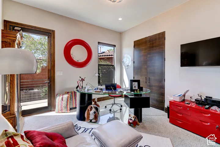 Recessed lighting, wood-finish double doors, a glass-top desk, a mounted television, and a glass-paneled exterior door