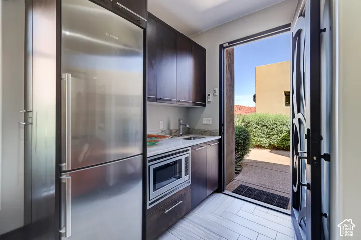 Stainless steel refrigerator and built-in microwave complement dark wood-finish cabinetry