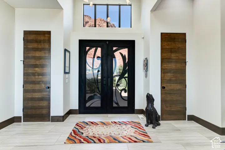Double entry doors with decorative ironwork, transom window, and vaulted ceiling