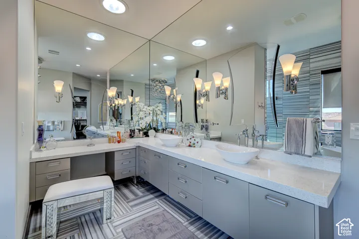 Dual vessel sinks, expansive vanity with integrated dressing table, wall-to-wall mirrors, recessed lighting, and patterned floor tiling