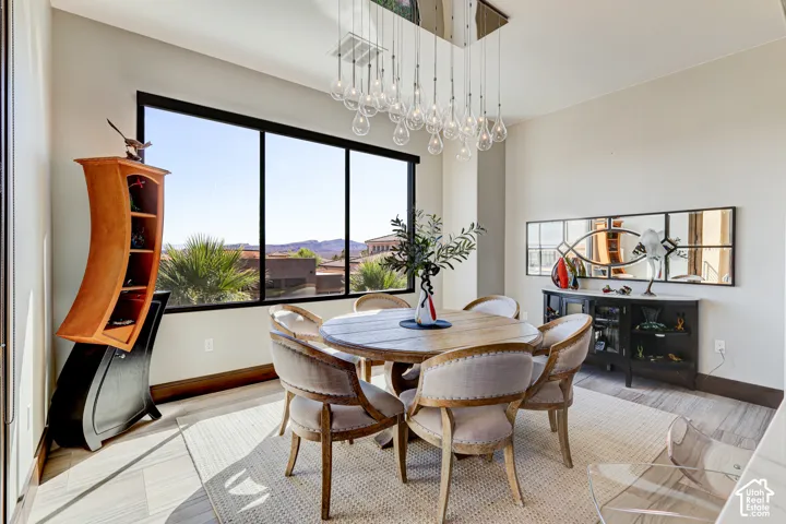 Expansive window with mountain scenery, contemporary suspended chandelier, and wood-finish flooring