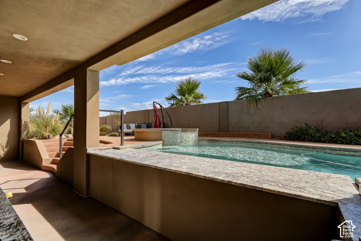 Covered patio with integrated lighting, a sparkling swimming pool, and an elevated spa