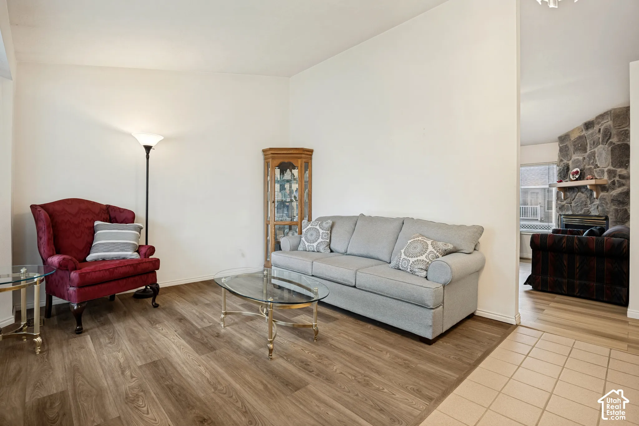 Wood-finish flooring, white wall finishes, and a stone-clad fireplace