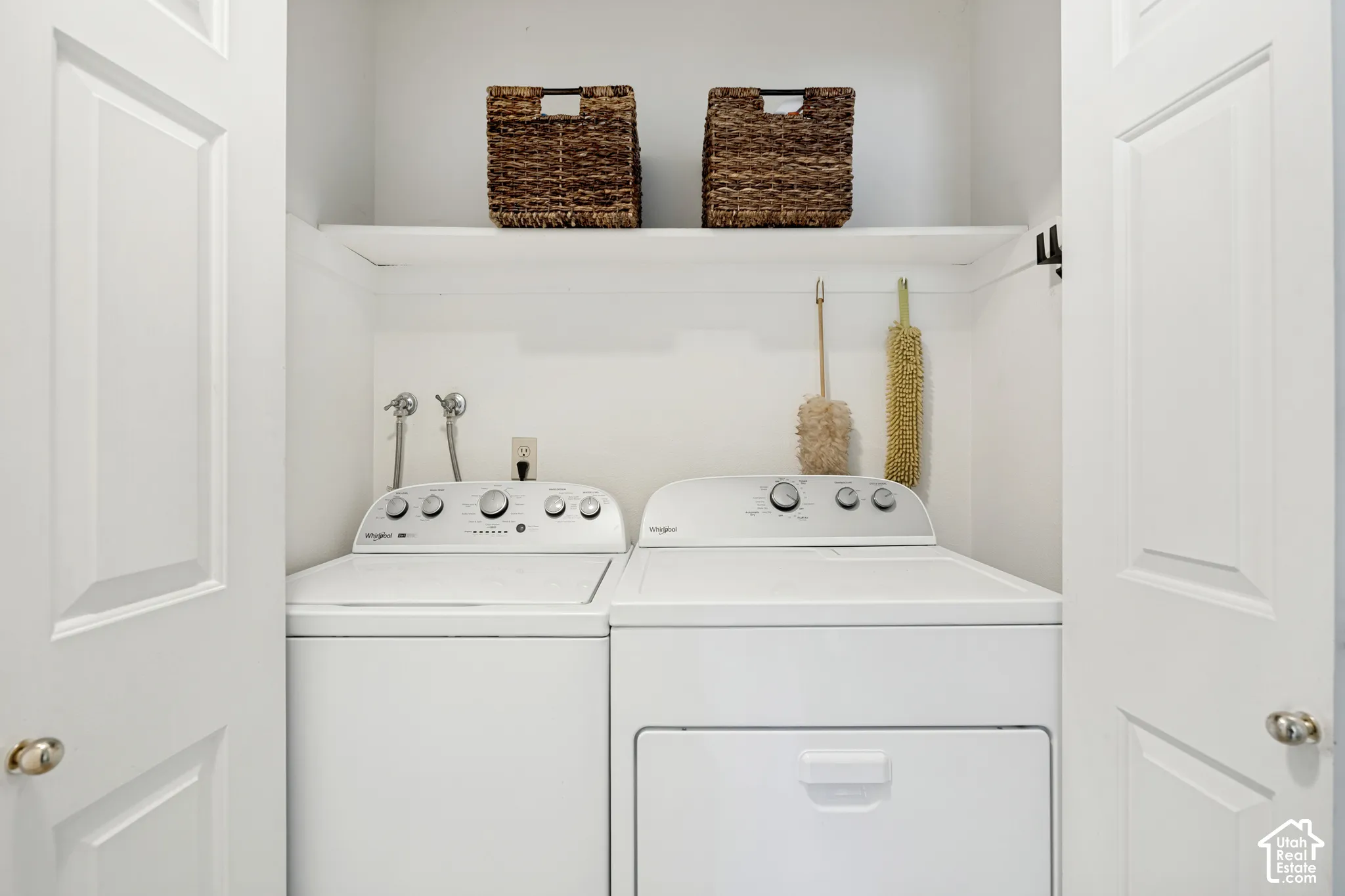 Dedicated laundry alcove with a built-in shelf and white paneled bifold doors