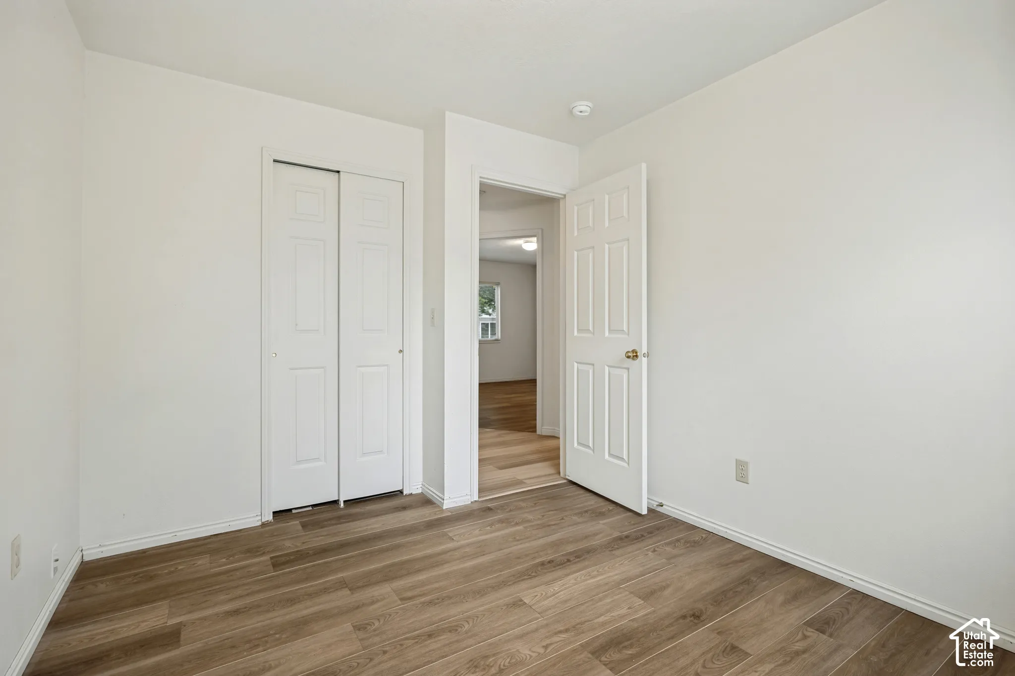Wood-finish flooring throughout, white walls, and a white sliding closet door
