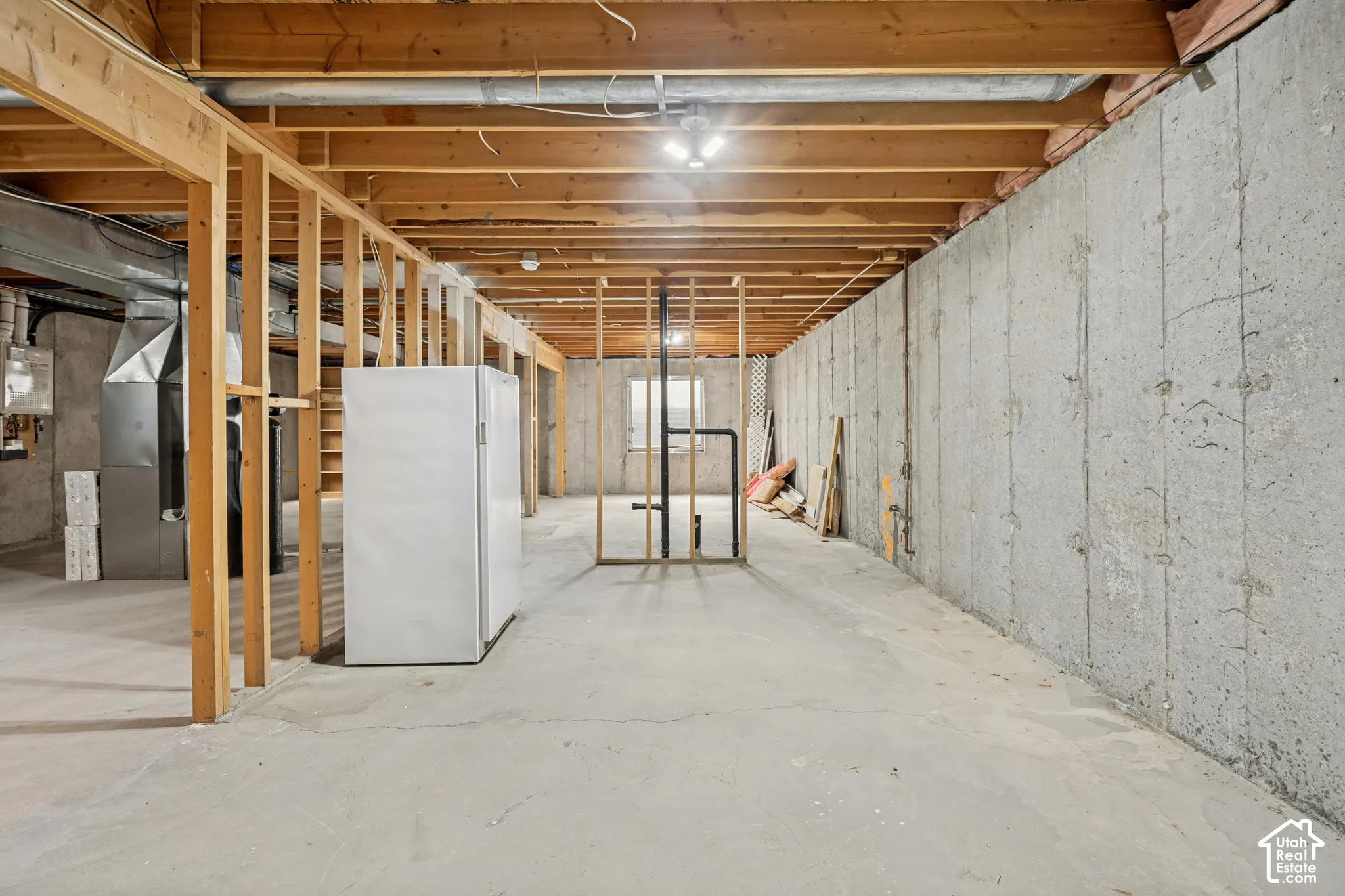 Unfinished basement with concrete flooring and exposed wood framing
