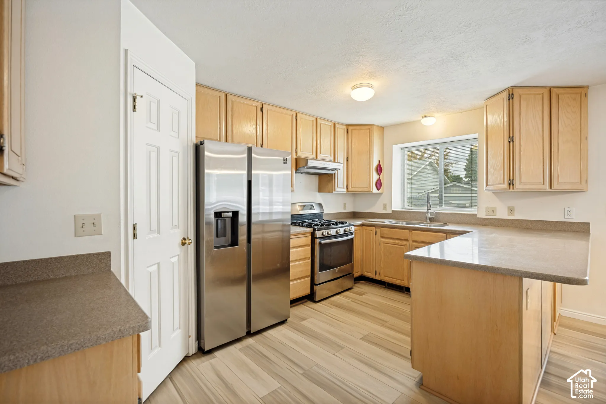 Full kitchen with wood-finish cabinetry, stainless steel appliances, and wood-finish flooring