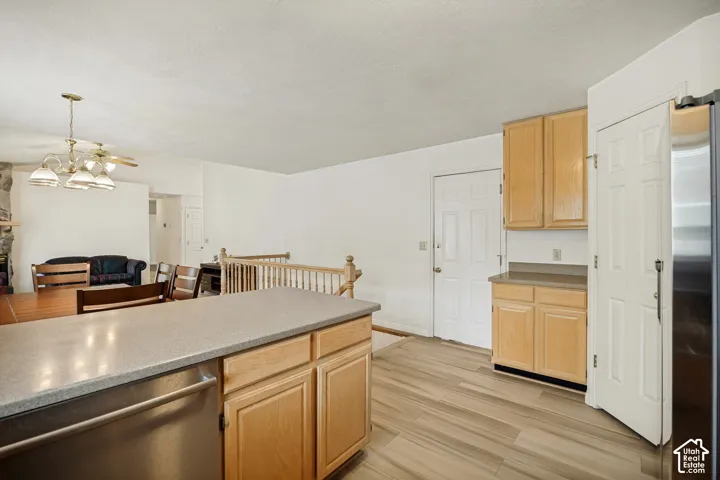 Kitchen featuring light wood cabinetry, a built-in dishwasher, and wood-finish flooring