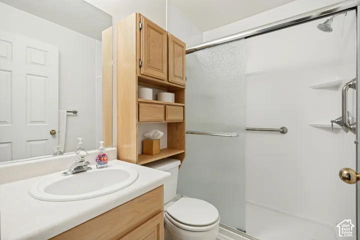 Bathroom featuring a vanity with an integrated sink, a built-in wood-finish cabinet with shelving, and a shower with a sliding frosted glass door