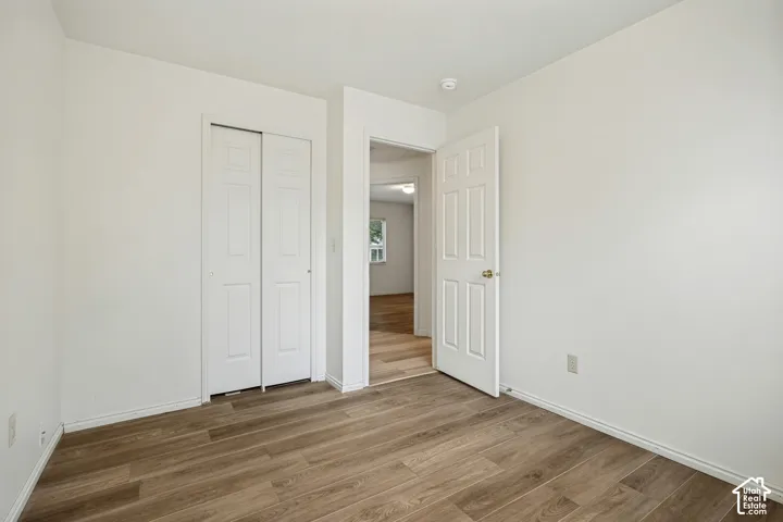 Wood-finish flooring throughout, white walls, and a white sliding closet door