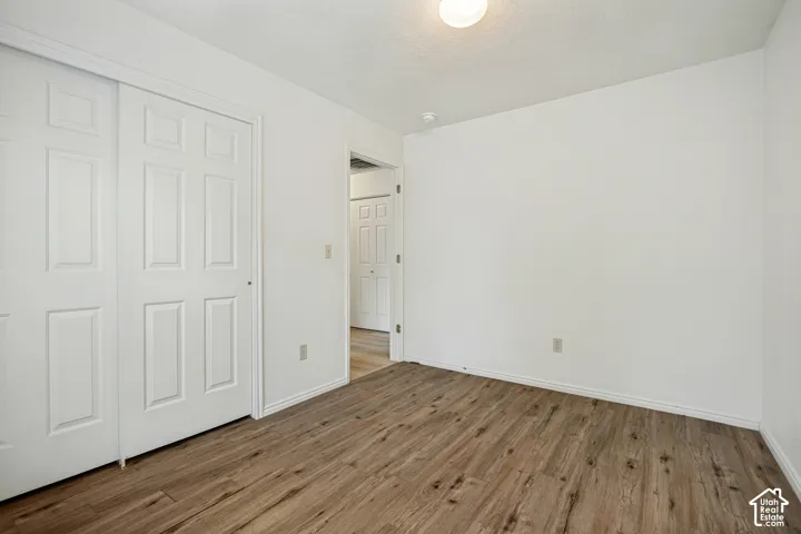 Wood-finish flooring, white walls, and a flush-mount ceiling light