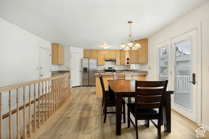 Wood-finish flooring throughout, kitchen with light wood cabinetry, stainless steel refrigerator, and built-in lighting