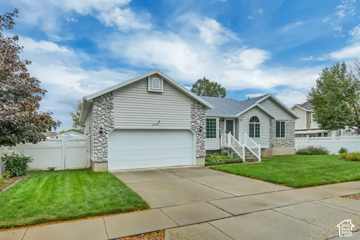 Exterior with stone veneer accents, light-toned siding, attached garage, and a concrete driveway