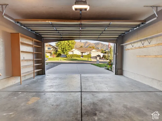 Concrete floor garage with built-in shelving, wall-mounted storage racks, and an automatic garage door opener