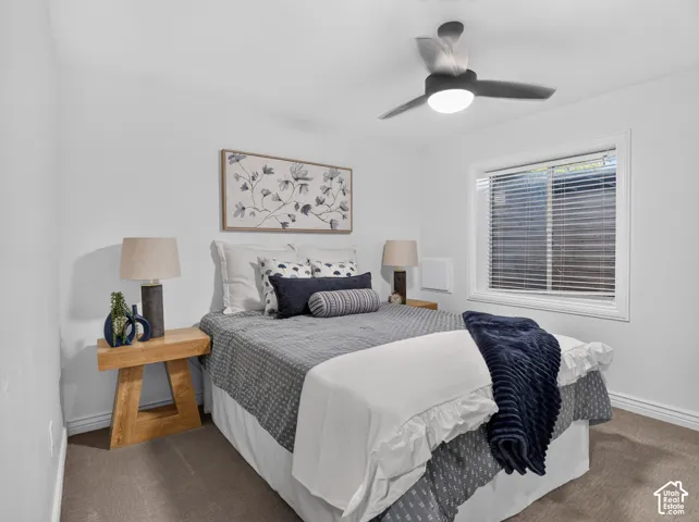 White walls with a single window, carpeted flooring, and a ceiling fan with integrated lighting