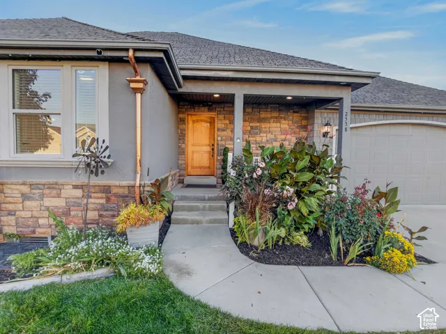 Stucco and stone facade with a covered porch entry, natural wood-finish door, and integrated garage