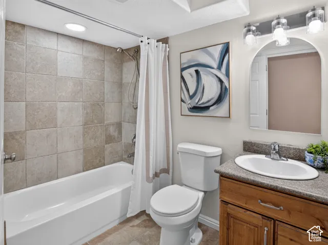 Bathtub with tiled surround, wood-finish vanity with countertop, and arched mirror