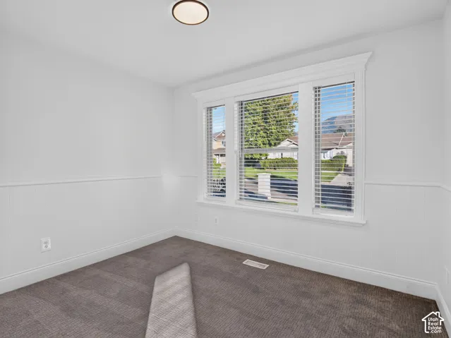 Window with white blinds, beadboard wainscoting, and neutral carpet flooring