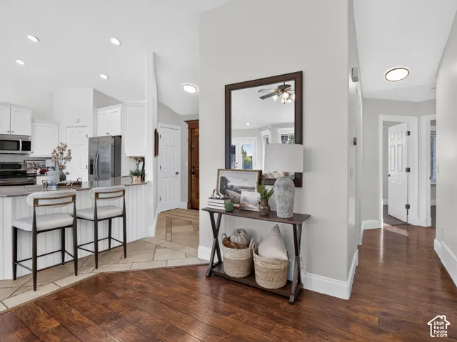 Wood-finish flooring, white cabinetry, stainless steel appliances, recessed lighting, and a kitchen island with seating