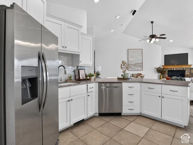 White cabinetry, stainless steel appliances, tile flooring, stone countertops, and a warm subway tile backsplash
