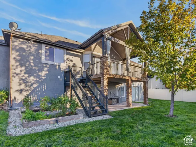 Two-story residence with a covered deck, stone-wrapped columns, and a lower-level patio