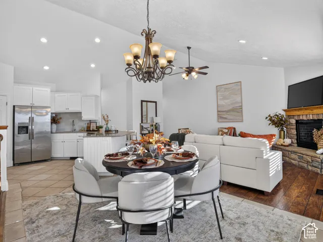 Open-concept living space featuring a stone-clad fireplace, vaulted ceiling, and recessed lighting