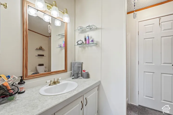 Vanity with integrated sink, brass-finish faucet, and wood-framed mirror