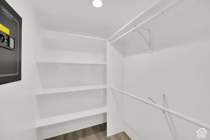 White wall-mounted shelving, multiple clothing rods, and wood-finish flooring