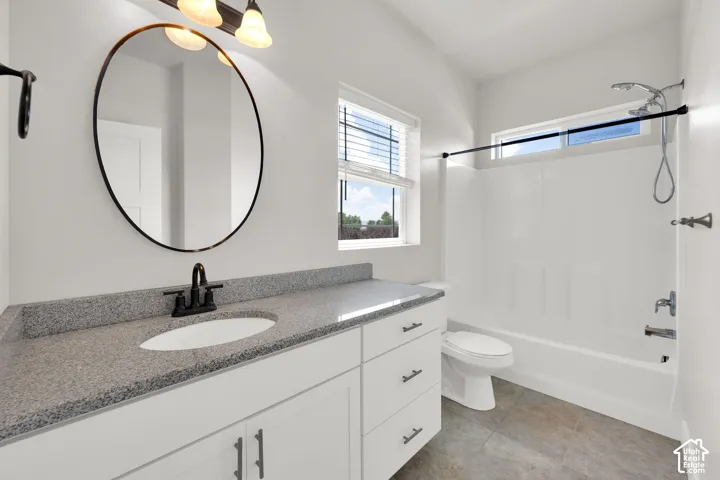 White vanity with a stone-finish countertop, undermount sink, and dark-finish faucet