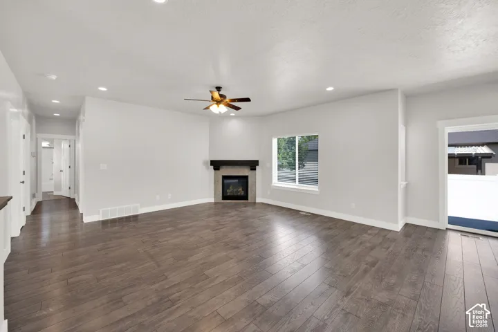 Spacious living area featuring wood-finish flooring, recessed lighting, and a modern fireplace with a dark mantel
