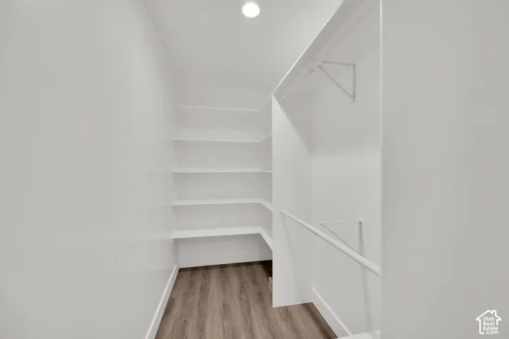 Recessed lighting, wood-finish flooring, built-in shelving, and white hanging rods