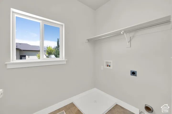 White-framed window, built-in shelving, clothes hanging rod, utility hookups, and a laundry pan