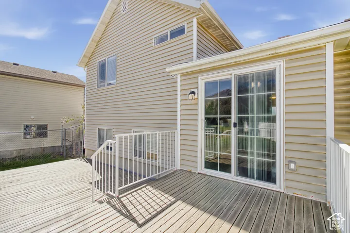 Expansive wood deck with white railings, sliding glass door, and vinyl siding exterior