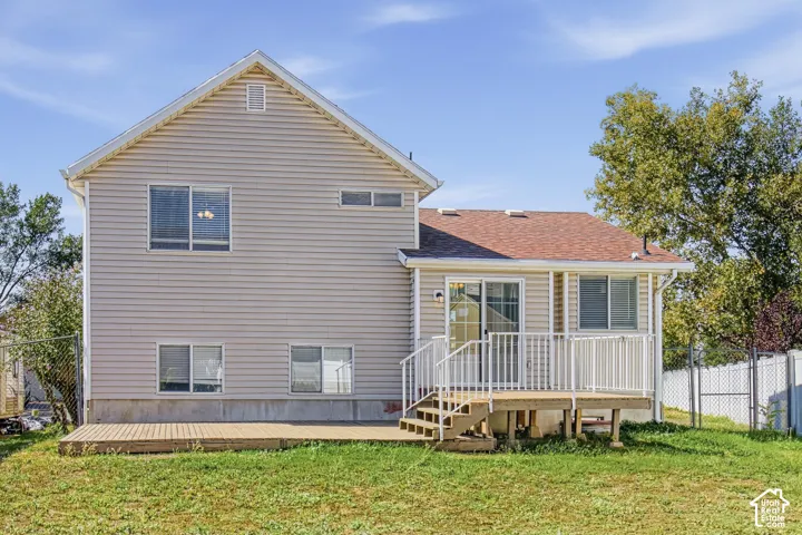 Rear exterior featuring light-colored siding, a multi-level deck with white railings, and a sliding glass door