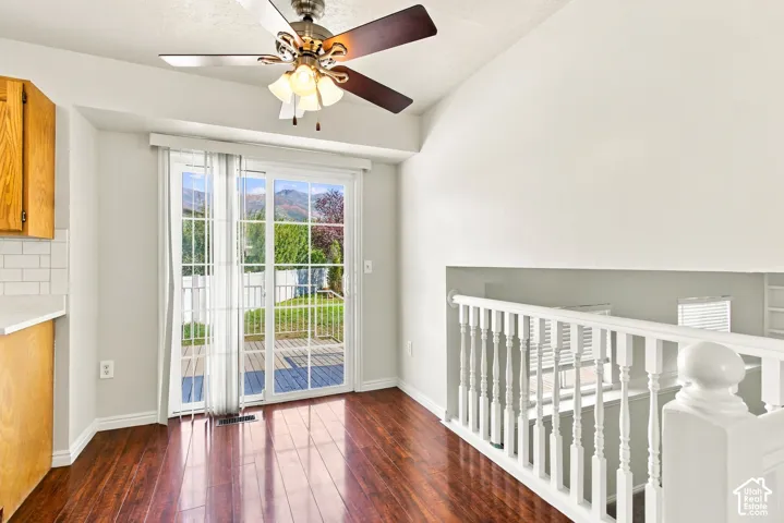 Wood-finish flooring, white spindle railing, sliding glass door, attached ceiling fan, and white subway tile backsplash