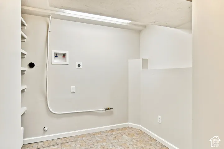 Laundry area featuring a utility sink connection, electrical outlet, and built-in shelving