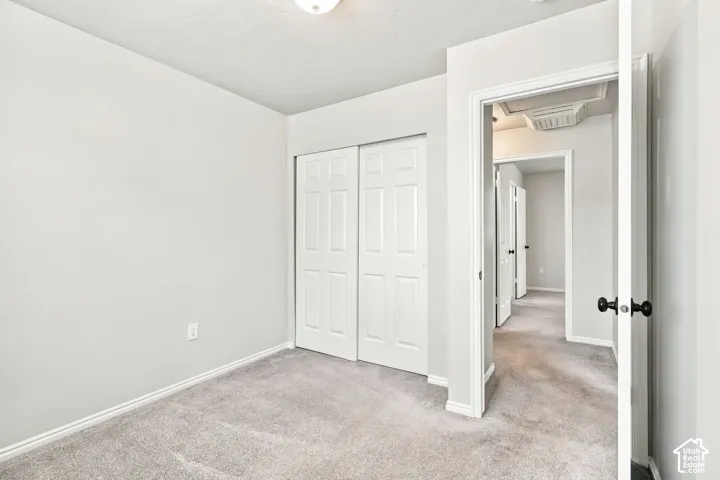 Light gray carpeting, white bi-fold closet doors, and a neutral wall color
