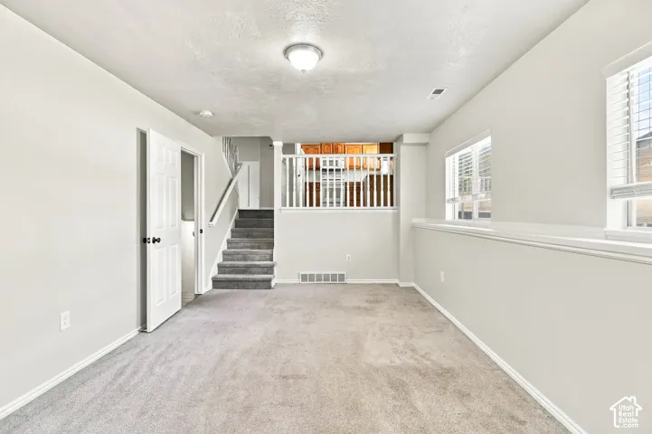 Recessed lighting, light gray carpeting, neutral wall finishes, white trim, and multiple windows with blinds