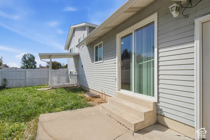 Sliding glass door access to the concrete patio, concrete steps, and covered side porch with railing