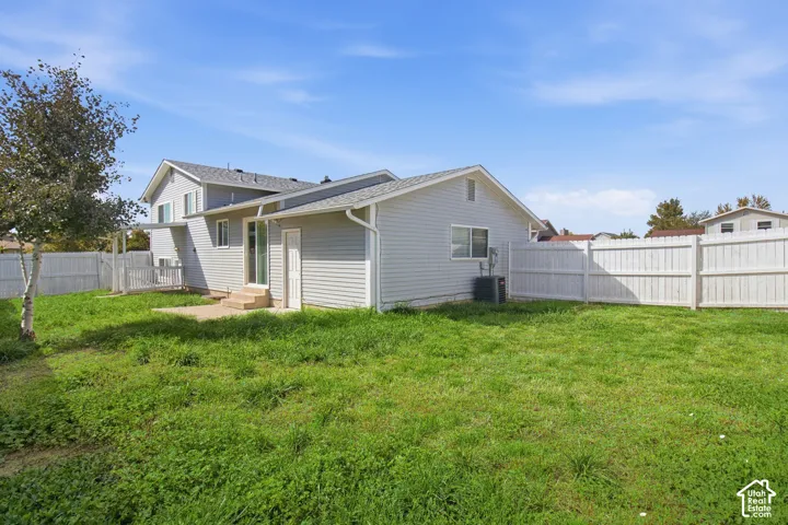 Expansive backyard with a manicured lawn, full fencing, and a concrete patio