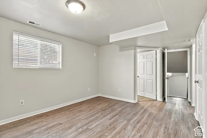 Wood-finish flooring with light gray walls, a flush-mount ceiling light fixture, and white baseboards