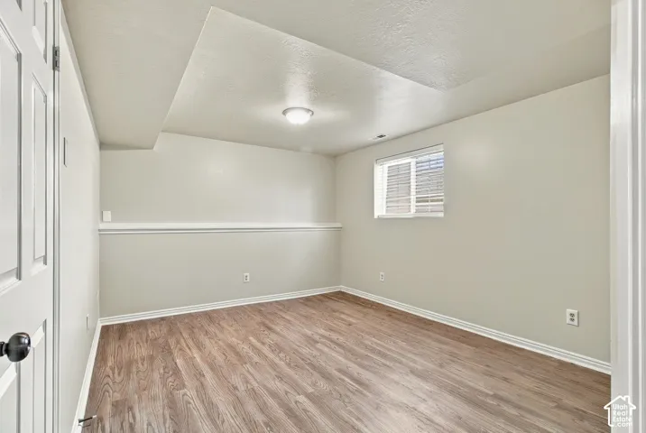 Recessed lighting, wood-finish flooring, single window with blinds, white trim, and a white paneled door