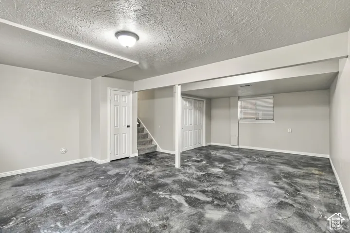 Spacious room featuring a concrete floor, light gray walls, and a recessed window with blinds