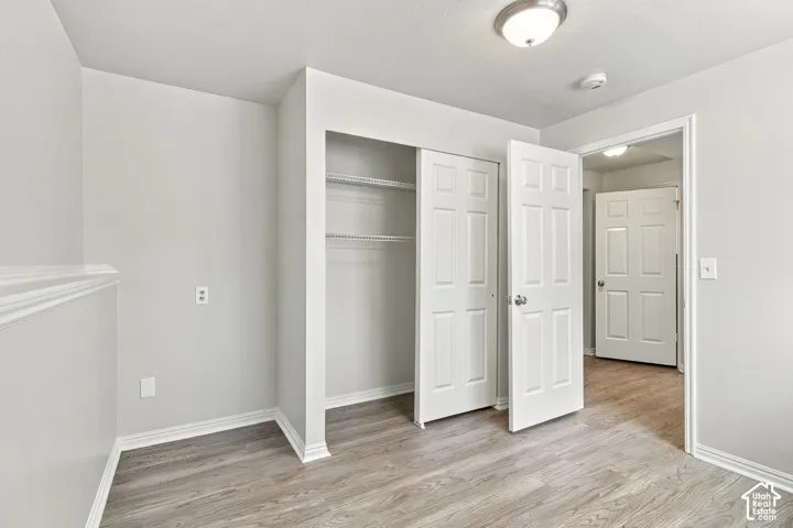 Wood-finish flooring, white trim, recessed lighting, bi-fold closet doors, and wire shelving