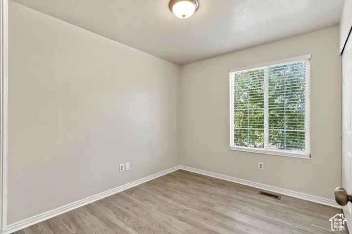 Recessed window with blinds, wood-finish flooring, and overhead lighting